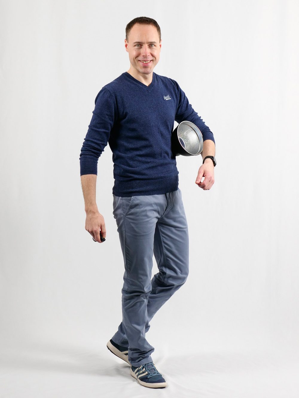 Dirk Sackmann lächelt in die Kamera und trägt einen Blitzreflektor unter dem Arm